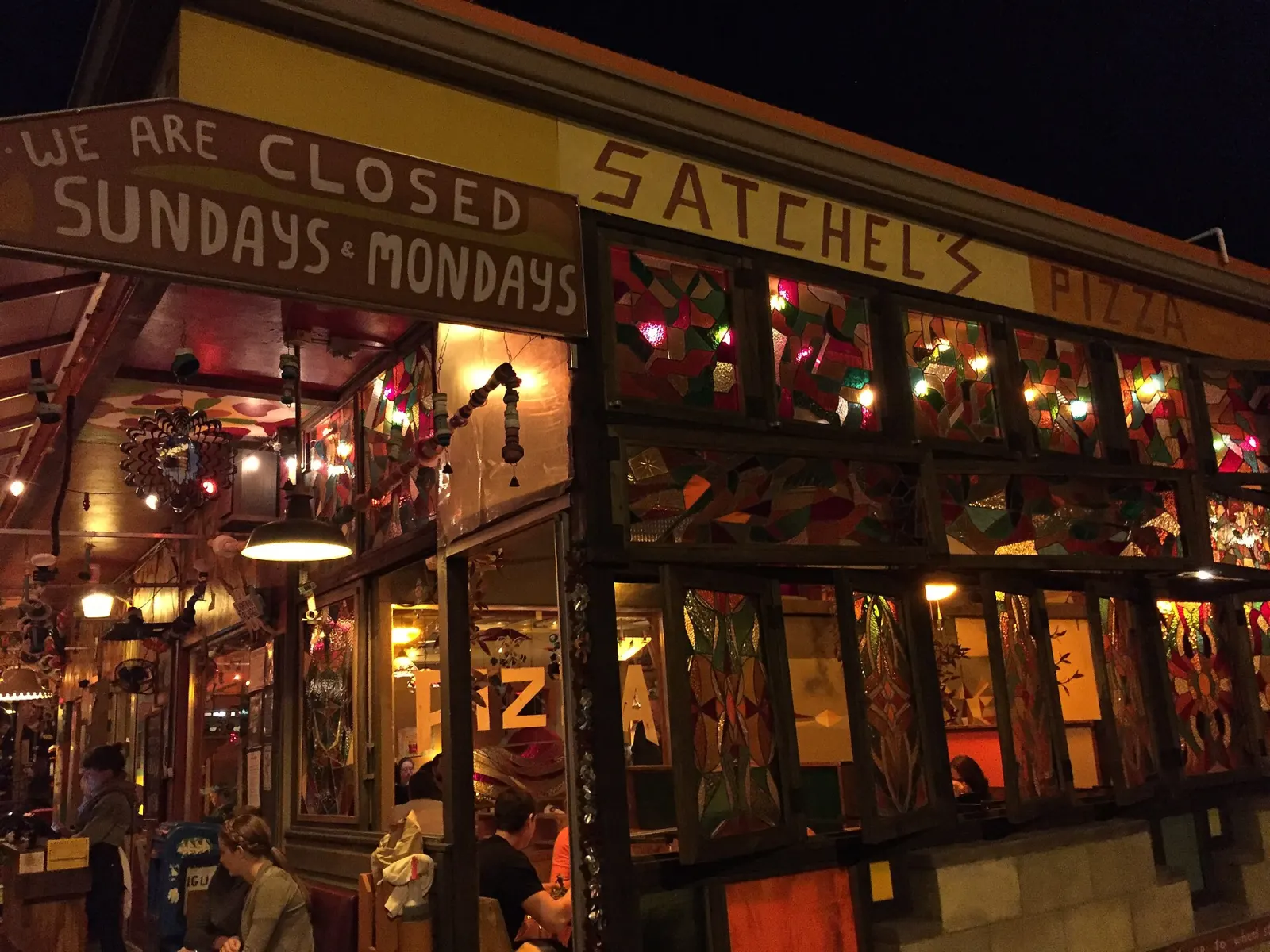 Diners at the open-air front of Satchel's Pizza on NE 23rd Avenue at night.
